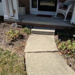 Front walkway leading to a house, with concrete path and surrounding landscaping, illustrating the entryway before foundation repair by Toledo Basement Repair.