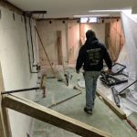 Worker inspecting basement renovation with exposed walls and construction tools, illustrating structural repair process for foundation issues.