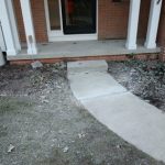 Concrete walkway leading to a home's entrance, showcasing foundation repair and landscaping improvements related to structural integrity and waterproofing.
