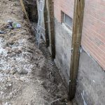 Excavated foundation wall with wooden supports and structural reinforcement, illustrating basement repair and waterproofing process for residential property in Perrysburg, Ohio.