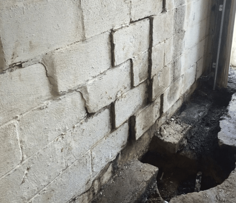 Severely bowing basement block wall showing structural foundation damage during repair work in Toledo Ohio