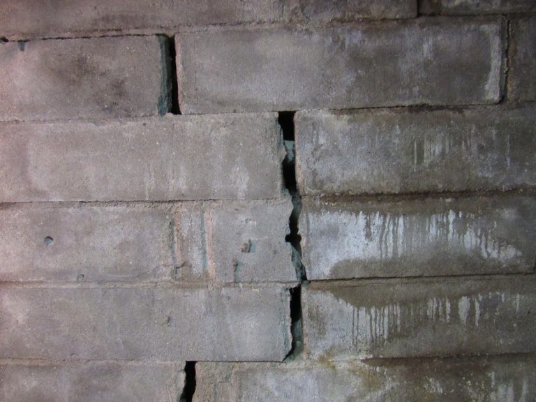 Large vertical structural crack in a concrete block basement wall indicating serious foundation damage.