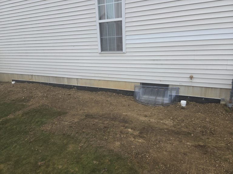 Completed exterior basement waterproofing project in Toledo, OH showing restored grading, foundation protection membrane, and waterproofed foundation wall.